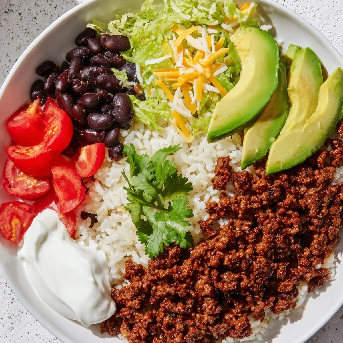 Close-up of a Beef Burrito Bowl with rice, seasoned beef, black beans, and fresh toppings, served in a rustic bowl.