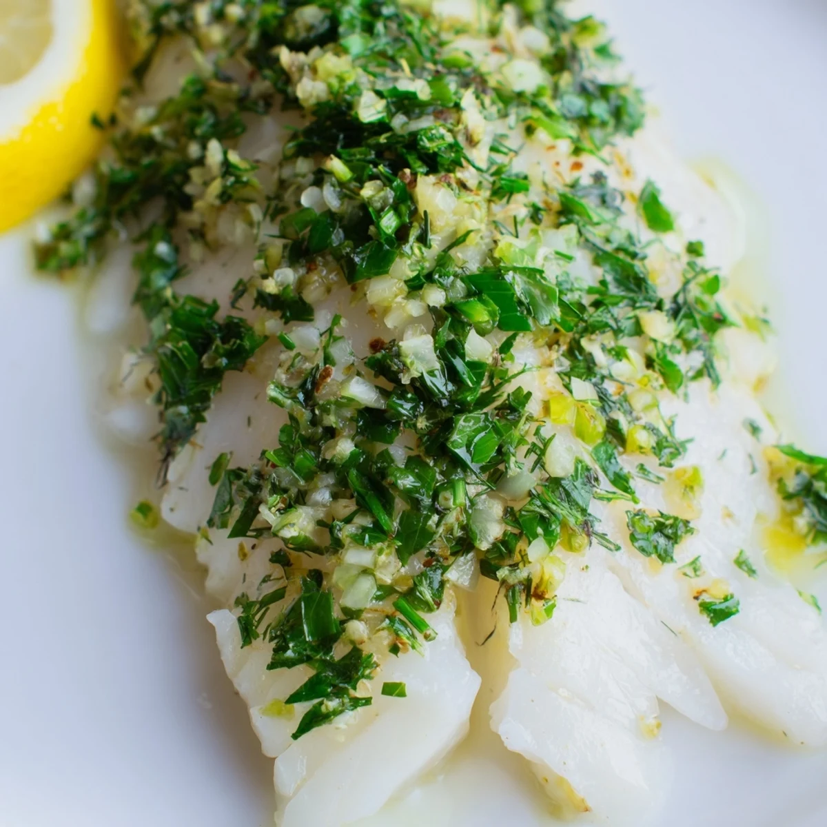 Freshly baked cod fillets with a colorful medley of parsley, dill, and garlic, arranged on a baking sheet beside lemon wedges for an easy weeknight dinner.