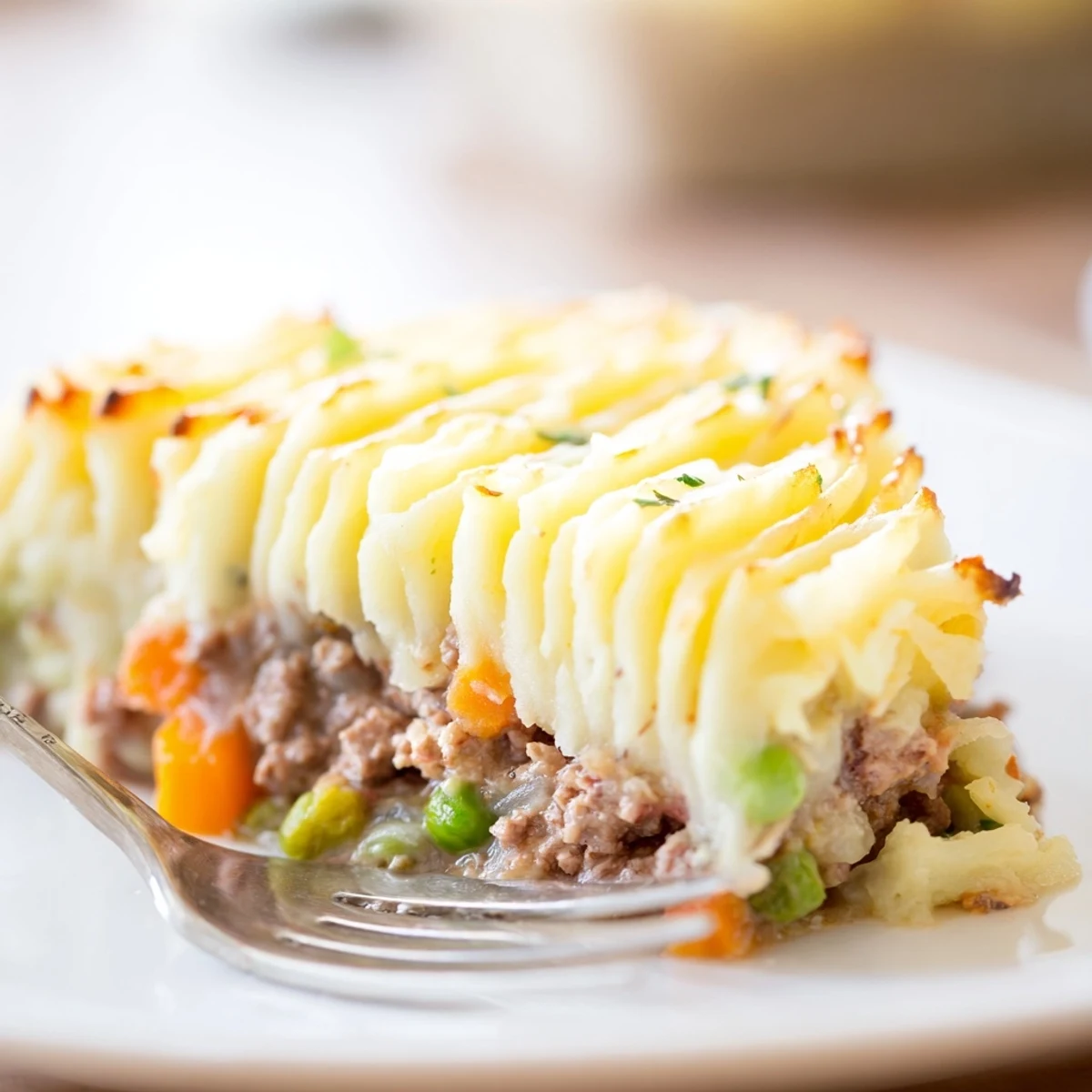 Golden-brown mashed potatoes top a bubbling beef Shepherds Pie with peas, served in a rustic white baking dish.  