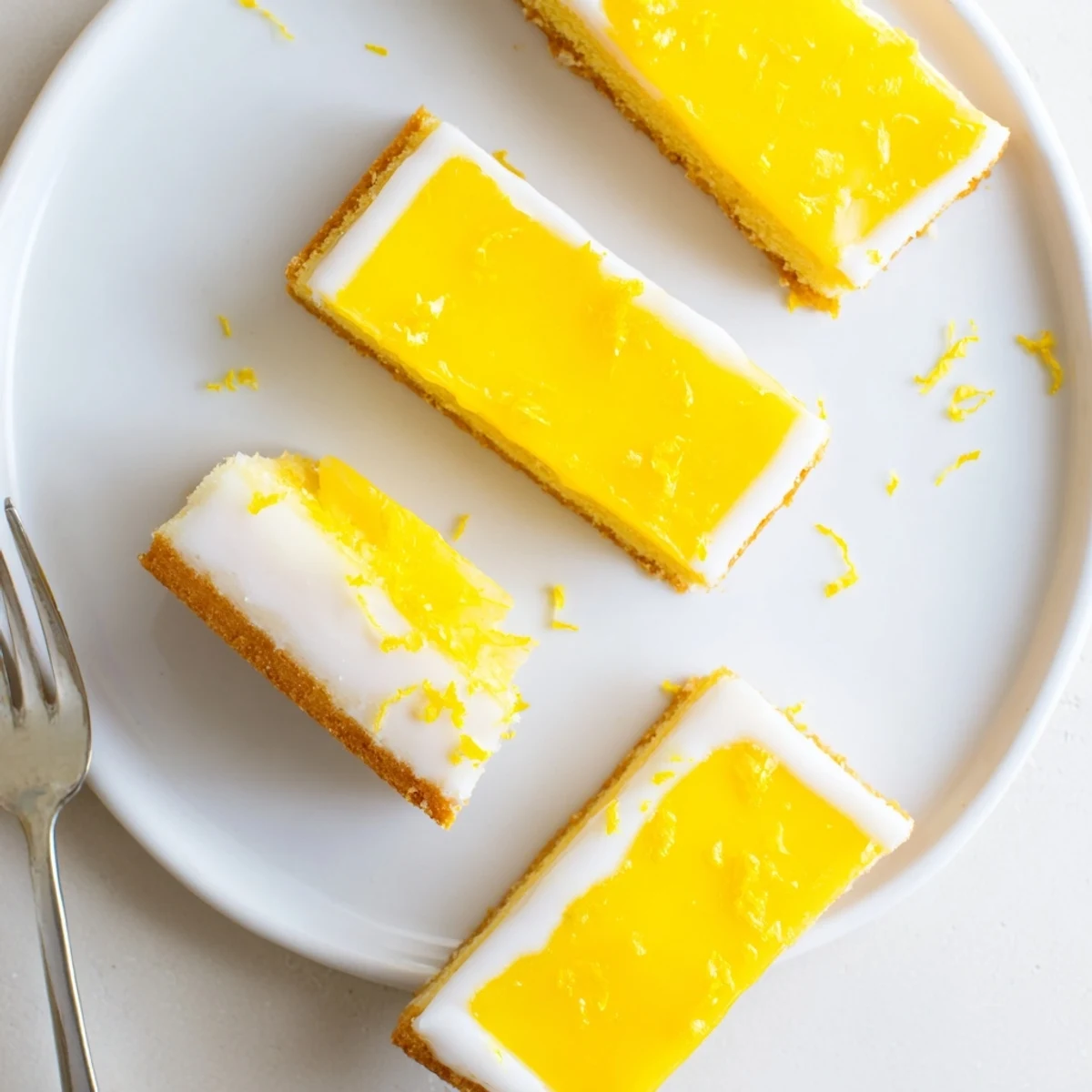 Homemade Lemon Dessert Bars are cut into squares, glistening with a zesty glaze and ready to serve on a dessert platter.