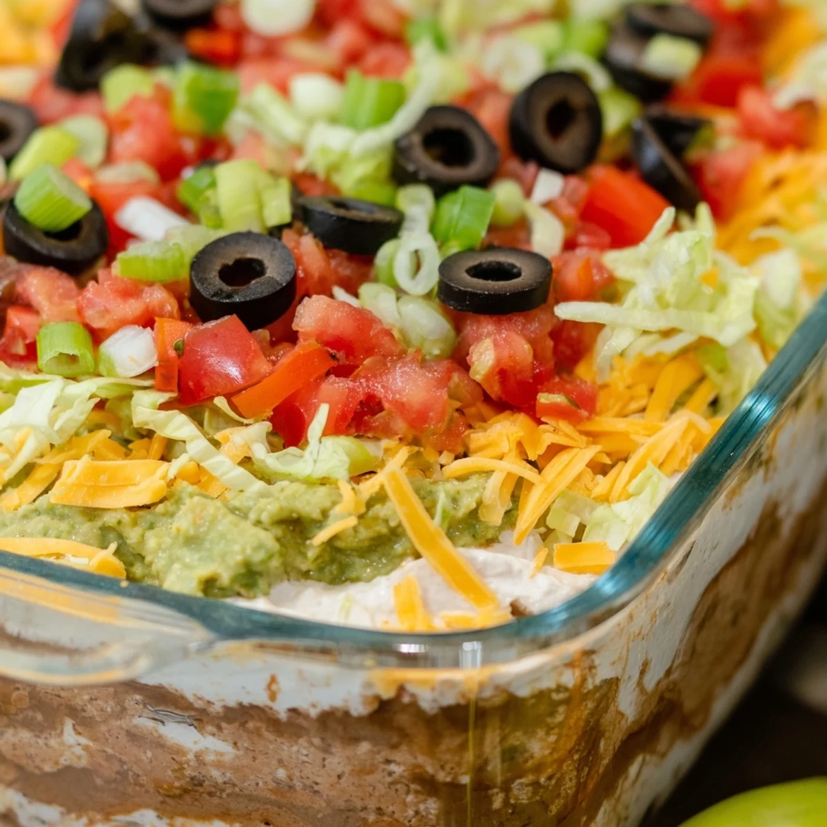 Chilled Tex-Mex Super Bowl Seven Layer Taco Dip showcases creamy refried beans, melted cheddar, and crisp lettuce toppings on a festive game day platter.