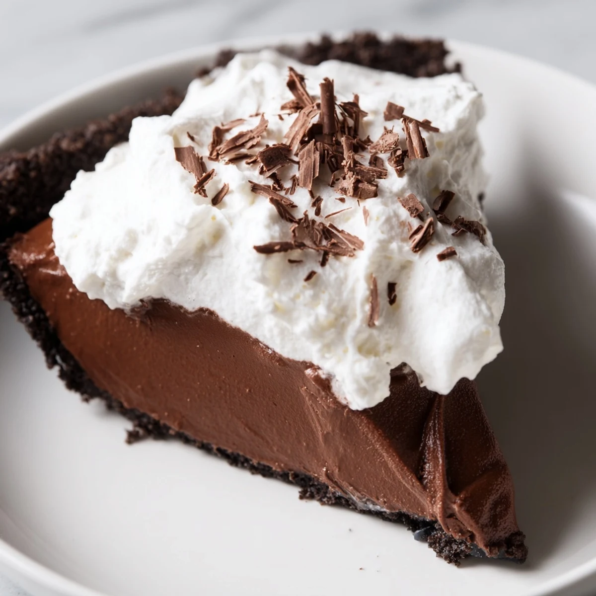 Rich, creamy chocolate silk pie in a dark cookie crust topped with fluffy vanilla whipped cream.