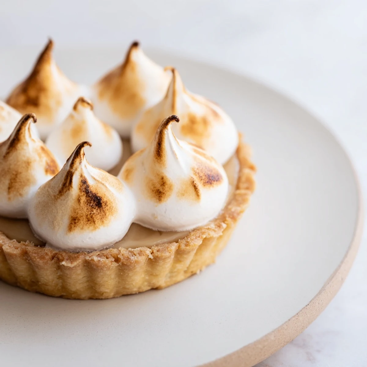 Freshly baked Irish Apple Amber Tart with a golden meringue topping and a slice on a plate, served with whipped cream.