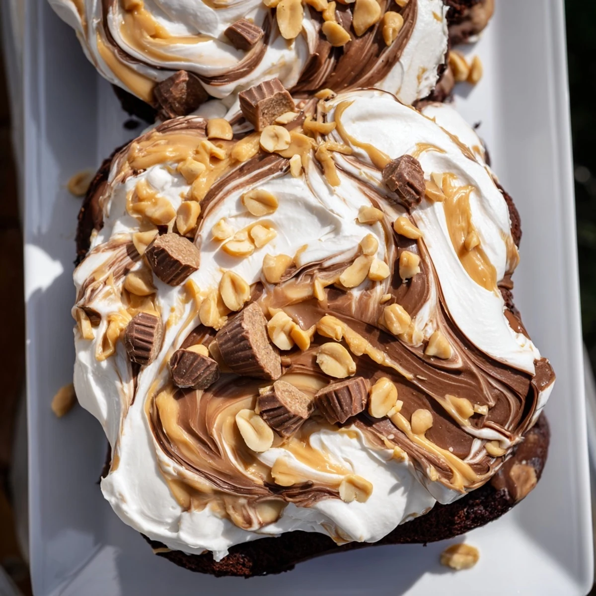 Decadent slice of chocolate peanut butter poke cake on a dessert plate, garnished with mini peanut butter cups and a cold glass of milk nearby.