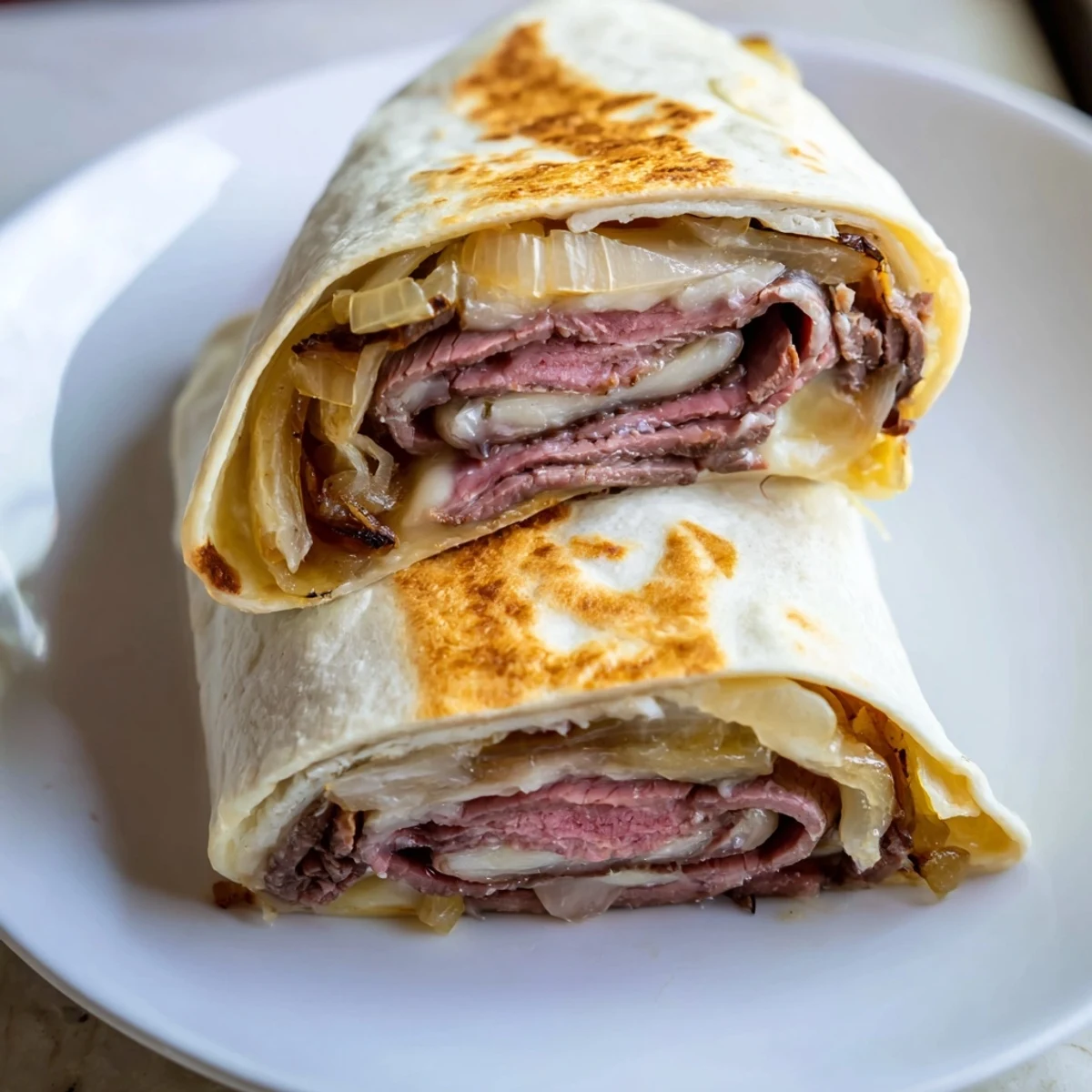 Close-up of Easy French Dip Tortilla Roll Ups, golden and crisp on the outside, oozing melted provolone and savory caramelized onions, served ready for dipping.
