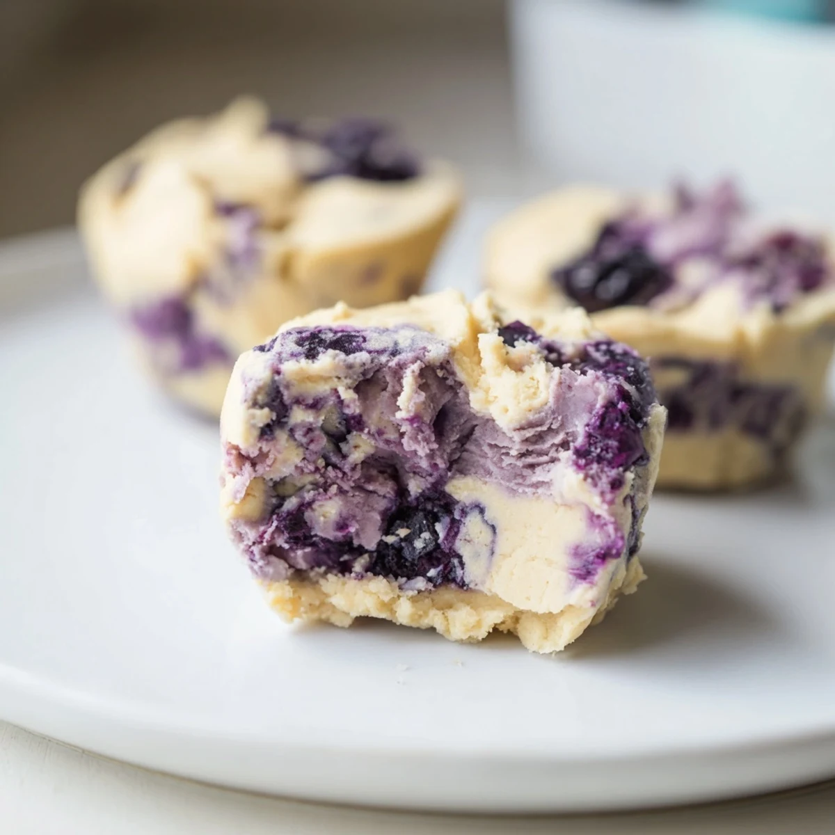 Arrange Blueberry Cheesecake Protein Bites on a marble board with fresh berries and a drizzle of maple syrup.