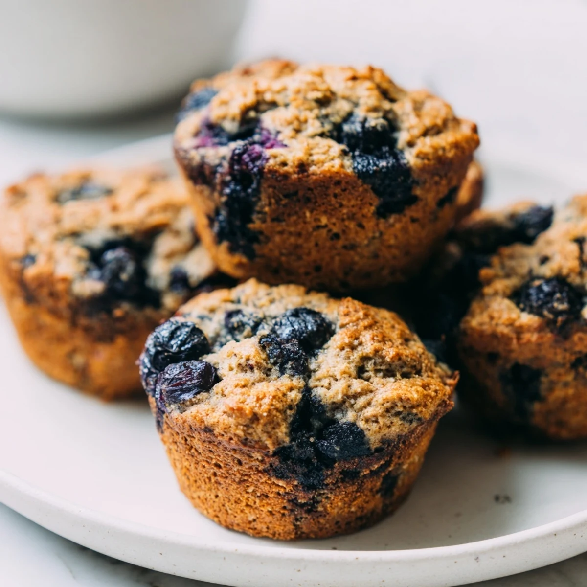 Twelve freshly baked Blueberry Protein Muffins with Greek Yogurt cooling on a wire rack, bursting with plump blueberries.  