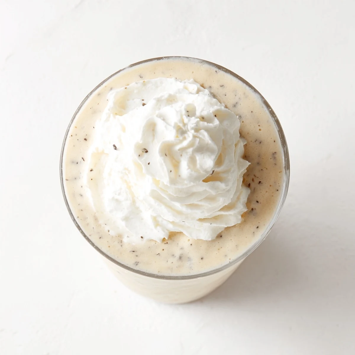 Starbucks Vanilla Bean Frappuccino topped with whipped cream in a tall glass, condensation on the side.