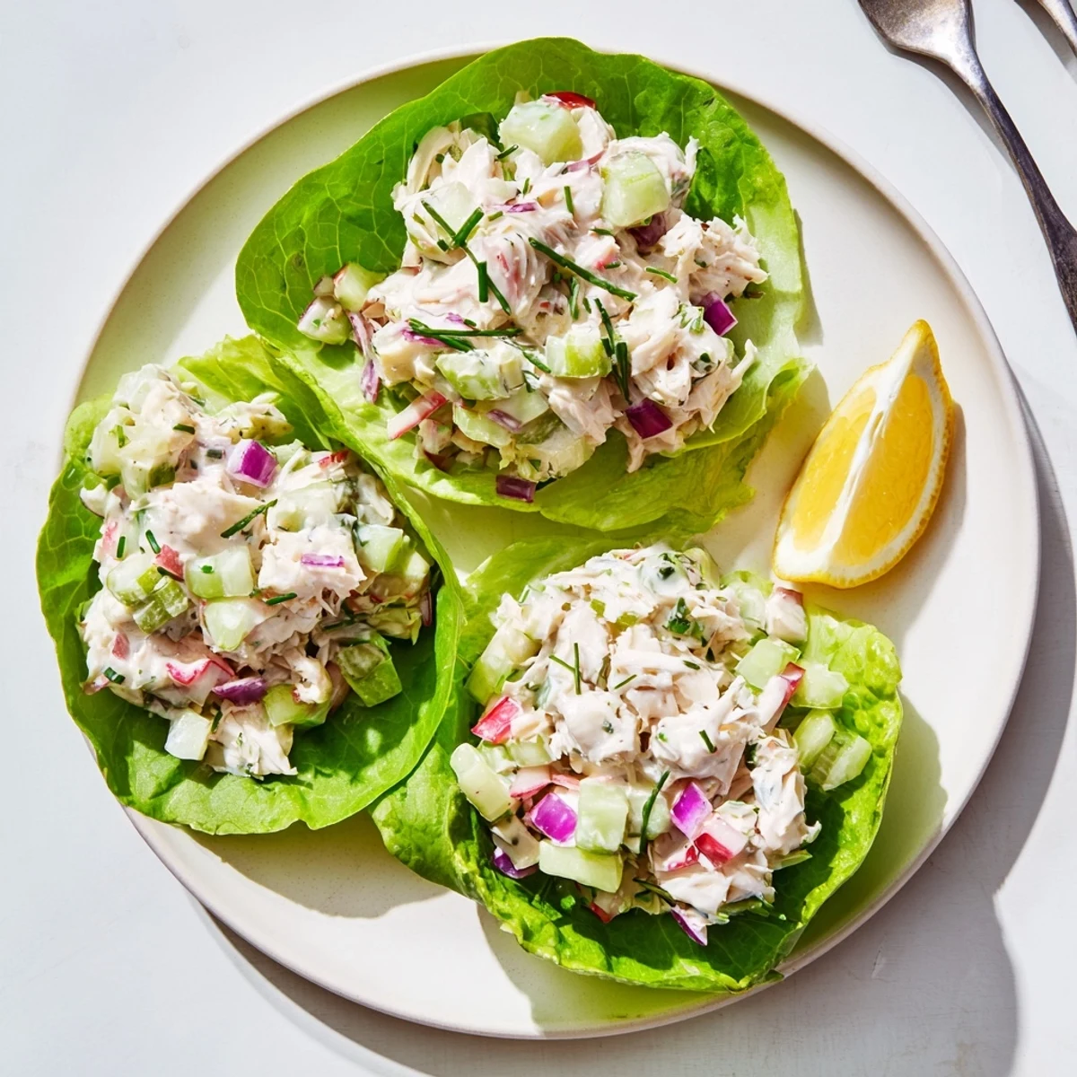 Light, tangy crab salad with red onion and parsley, presented on mixed greens with lemon wedges.