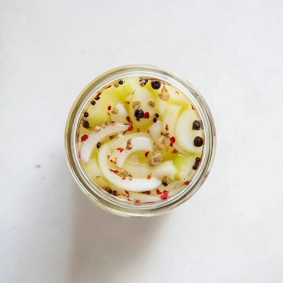 A close-up of Quick Pickled Celery with vibrant green pieces and spices, ready to garnish Bloody Marys or elevate a fresh cucumber salad.