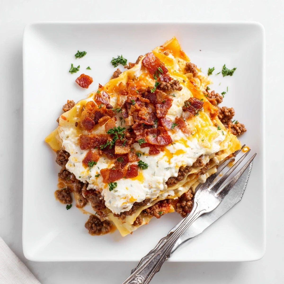 Crispy bacon crumbles top the hearty Lasagna Meets Cheeseburger Parmesan Garlic Bacon Style ready to slice.