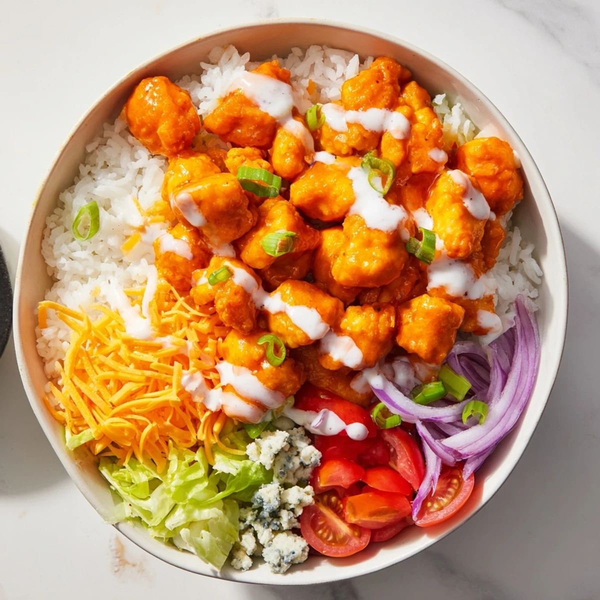 Served Buffalo Chicken Bowls with tender buffalo chicken, fresh carrots, tomatoes, and cool ranch over rice.