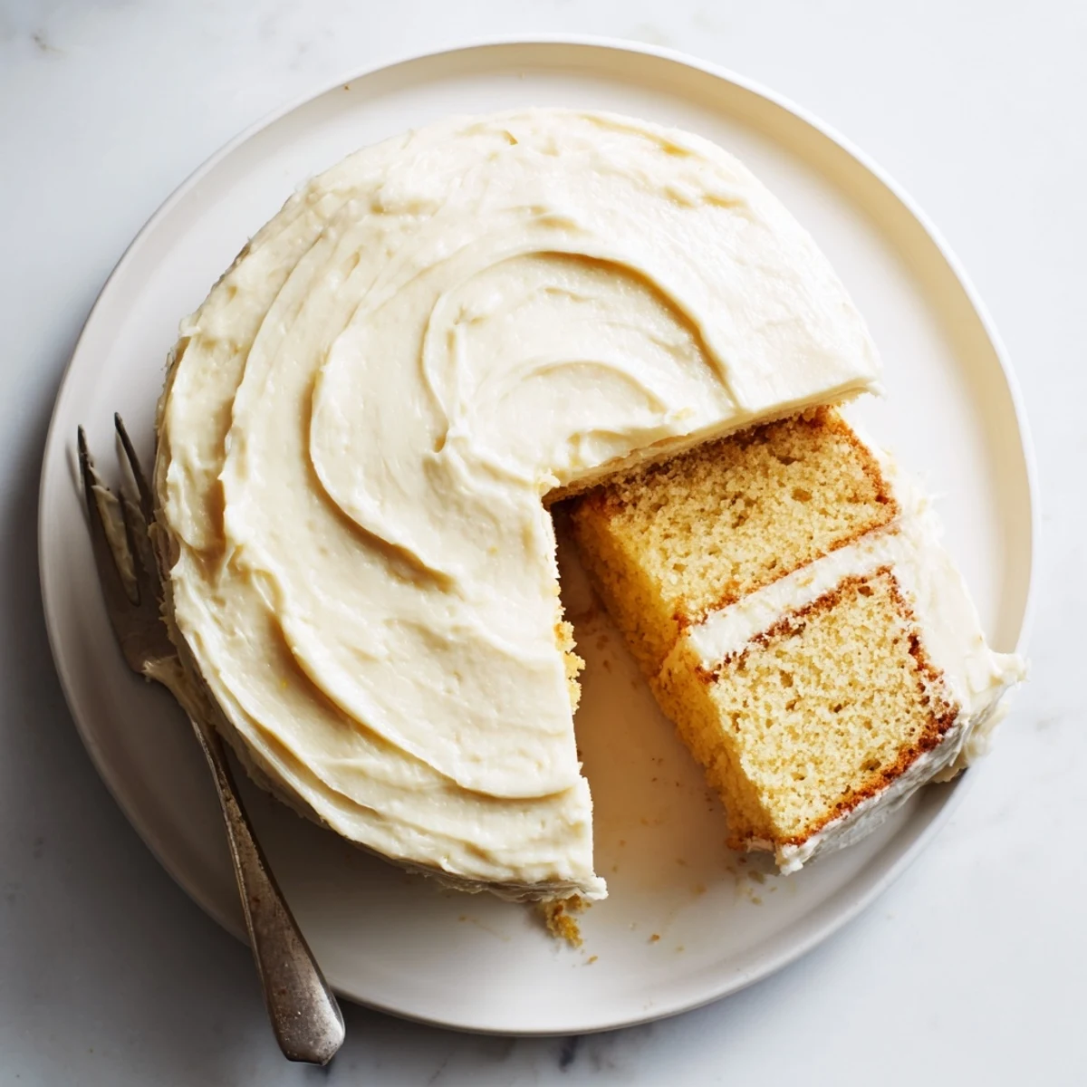 A slice of Perfect Vanilla Cake with creamy buttercream frosting, ready to serve at a celebration.