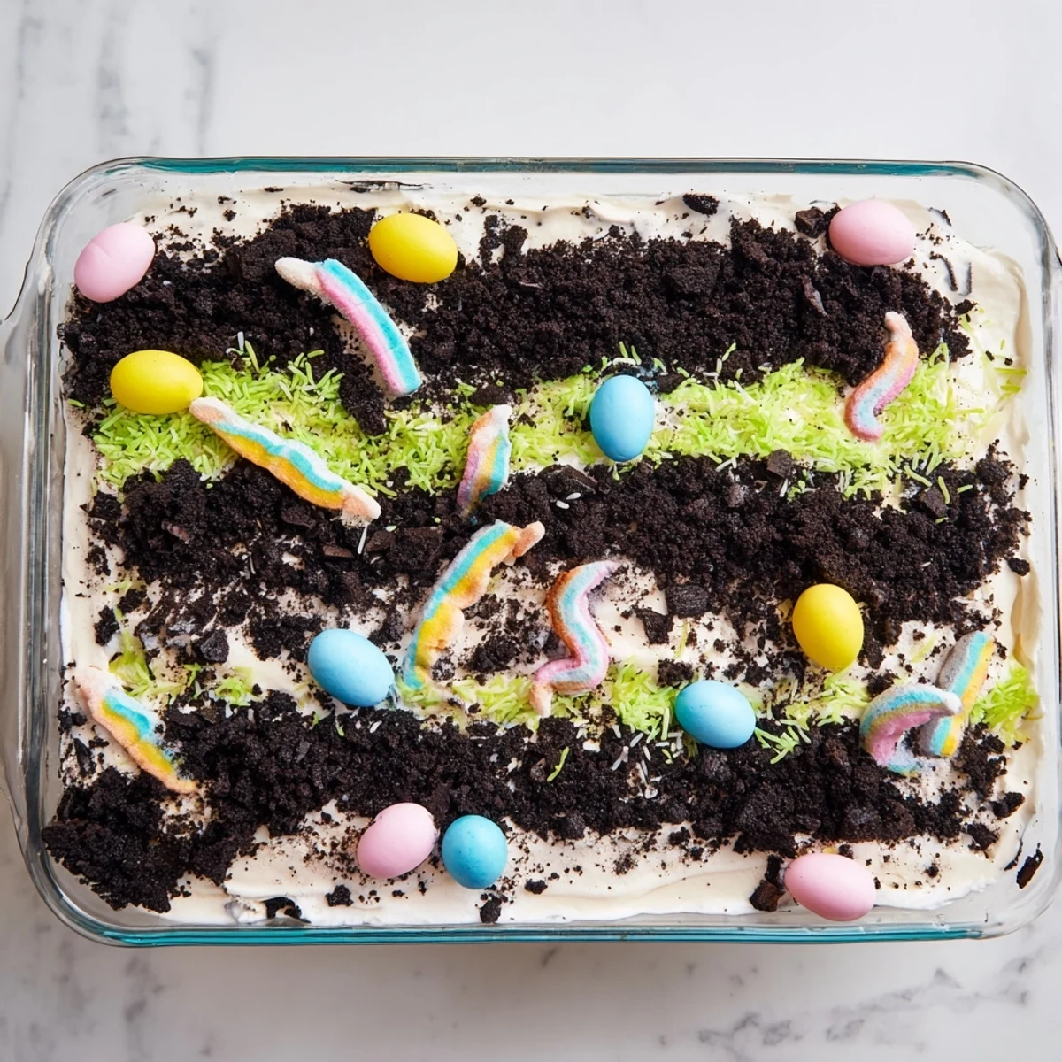 Easter Dirt Cake Casserole with gummy worms and pastel eggs in glass dish