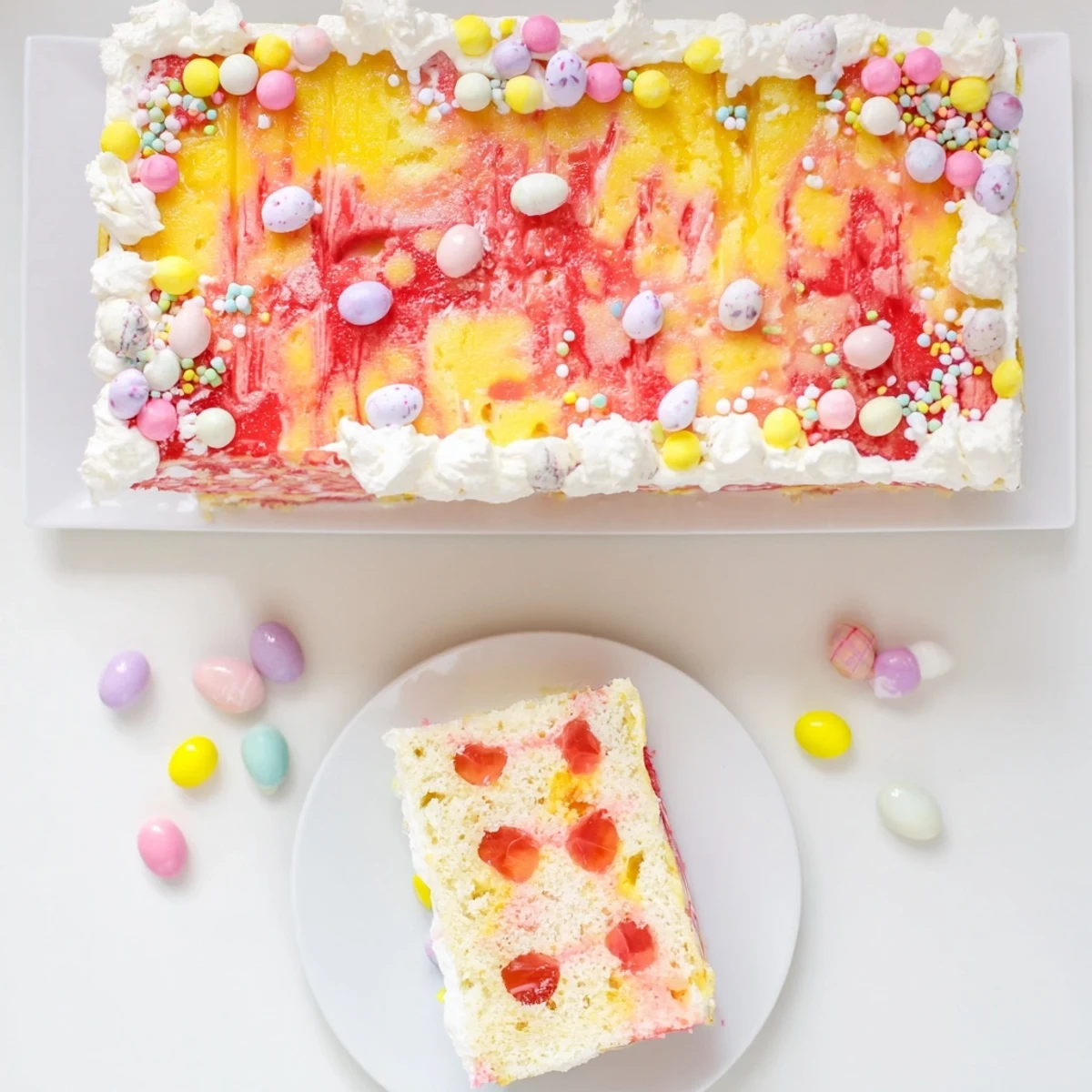Spring dessert featuring moist vanilla cake poked with strawberry and lemon gelatin beneath sweet whipped cream