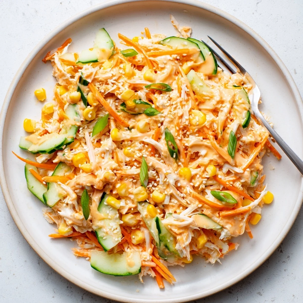 Colorful bowl of spicy kani salad tossed with creamy sriracha dressing and crisp julienned vegetables