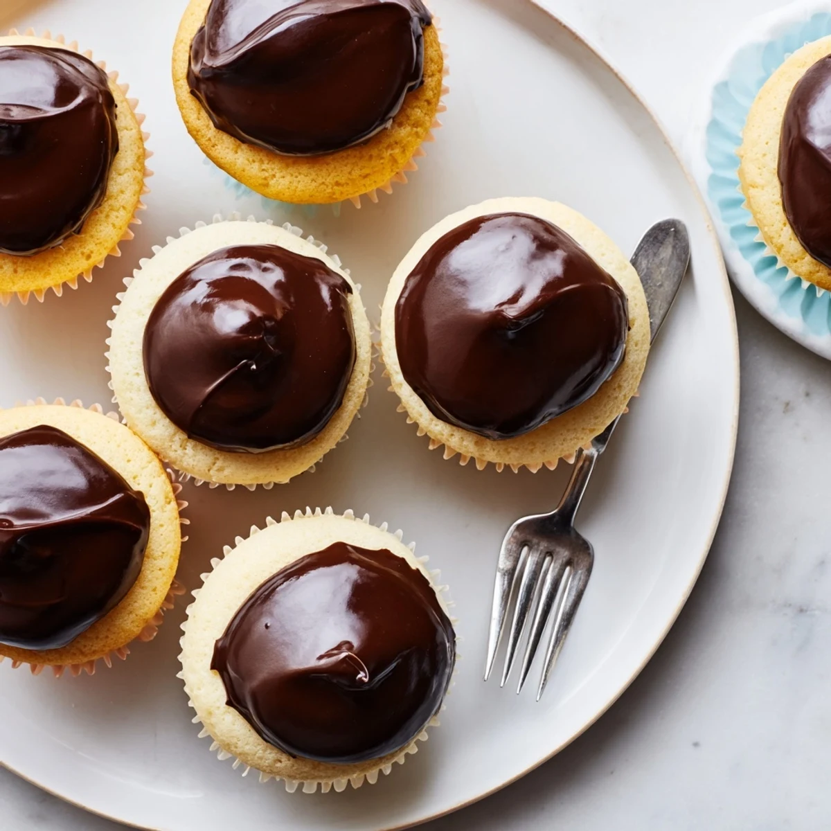 Rich chocolate glazed Boston cream pie cupcakes with soft vanilla cake and smooth custard filling