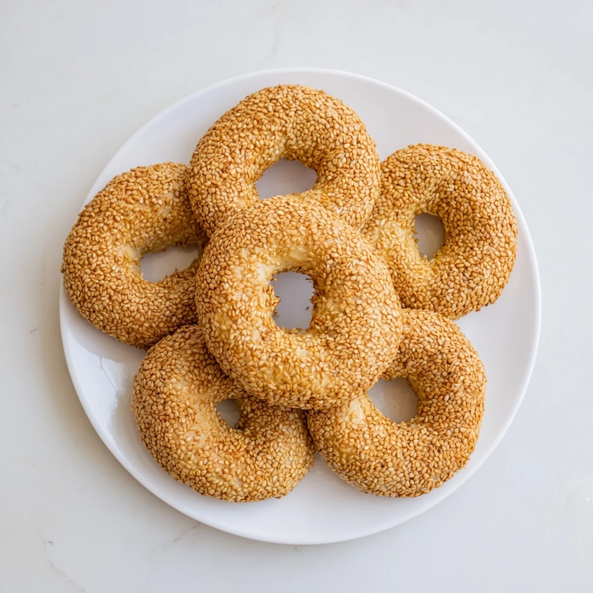 Mediterranean-style sesame bread rings coated in toasted seeds, perfect for breakfast or snacking with olive dip.