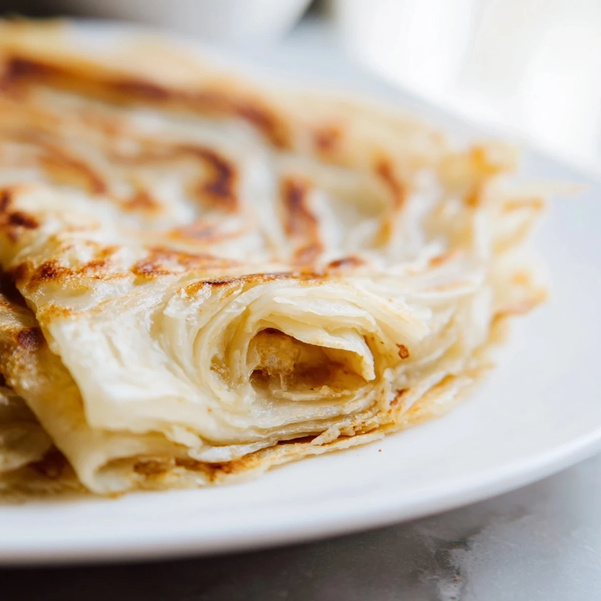 Hot Malaysian roti canai being cooked until golden brown in a skillet