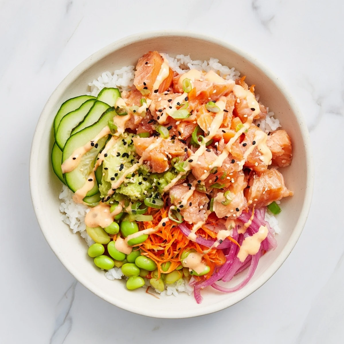 Flaky baked salmon bowl with fresh avocado, cucumber, and spicy sriracha mayonnaise drizzle