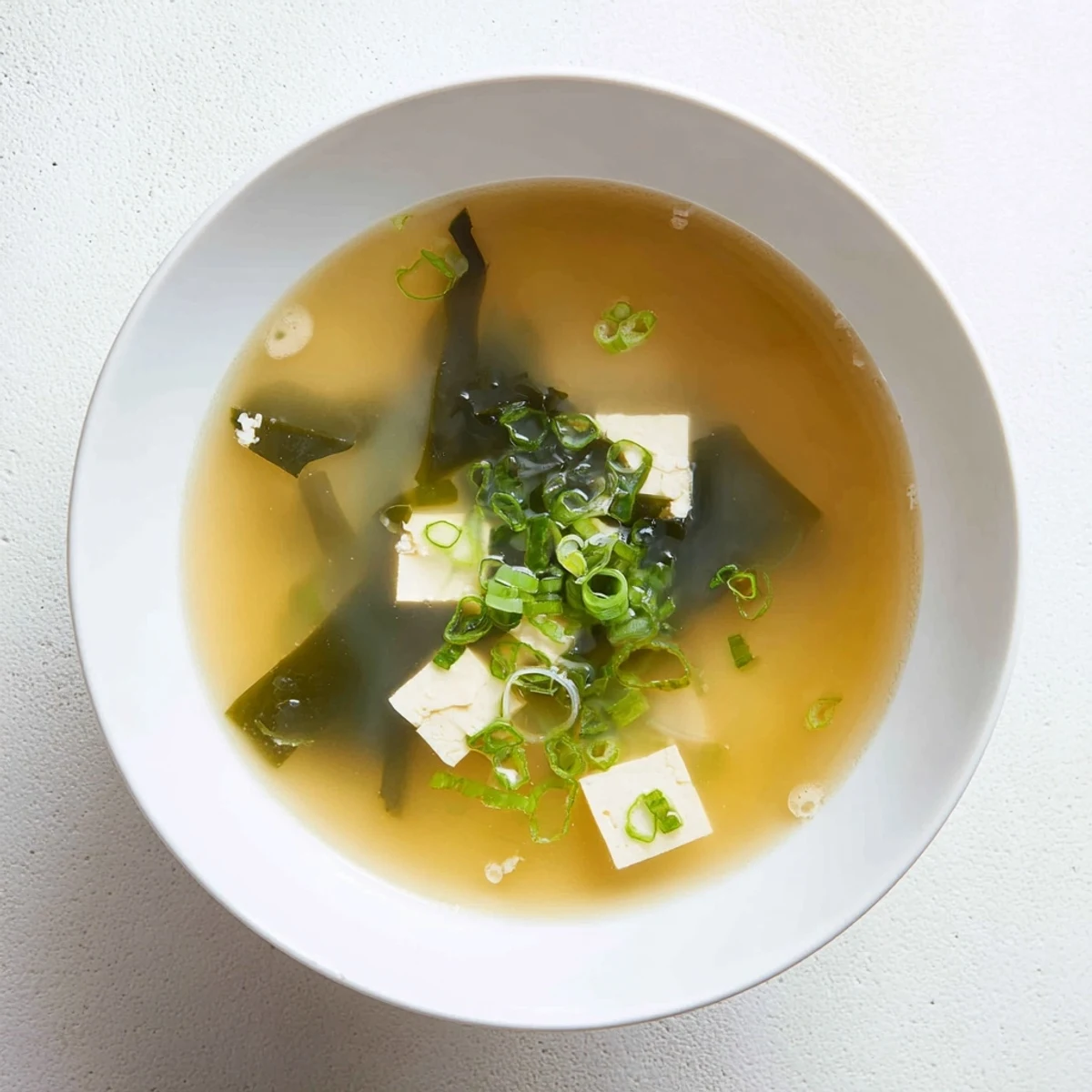 Steaming bowl of easy authentic miso soup with soft tofu cubes and green onion garnish