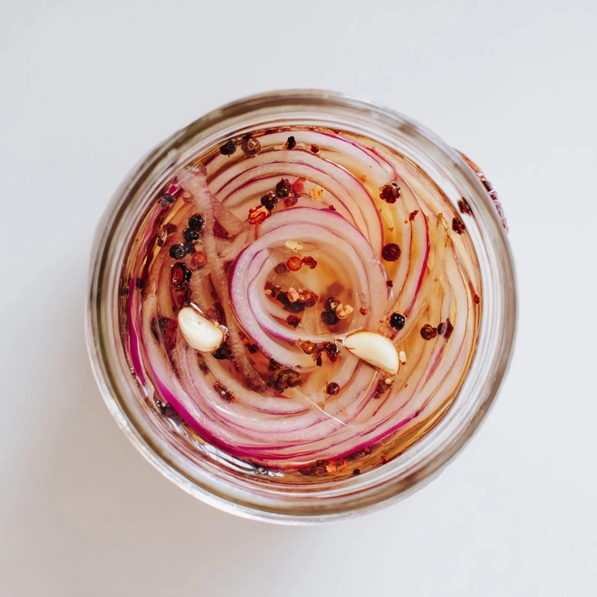 Tangy red onion slices submerged in golden honey vinegar brine with red pepper flakes