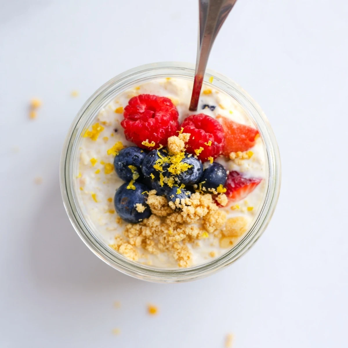Golden jar of zesty lemon cheesecake overnight oats layered with tangy Greek yogurt and bright lemon zest garnish