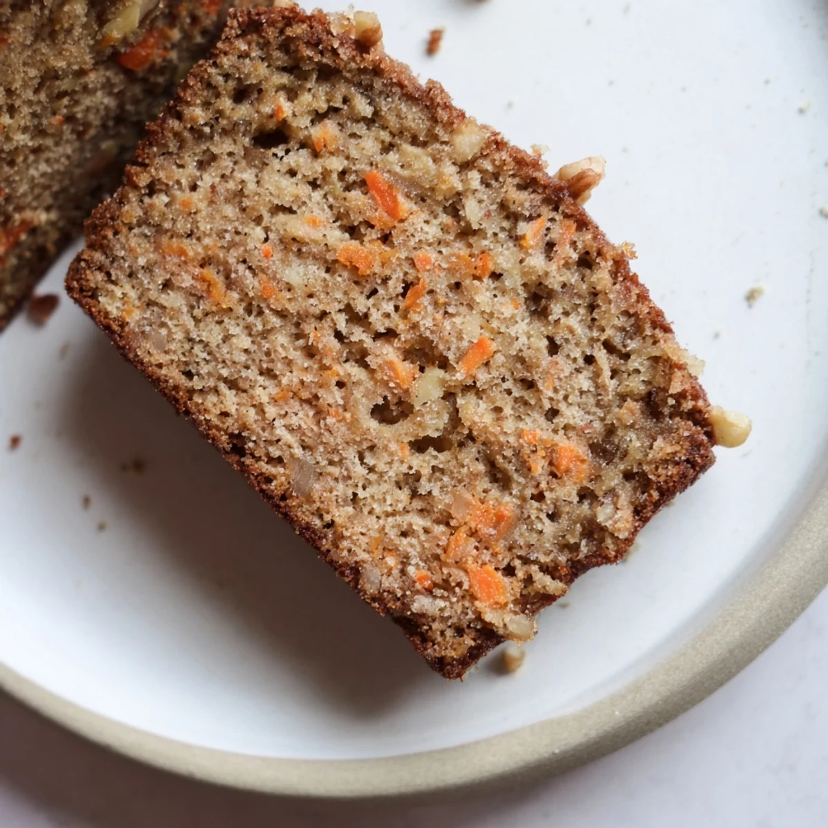 Freshly baked spiced carrot cake banana bread cooling on wire rack with visible flecks of orange carrot