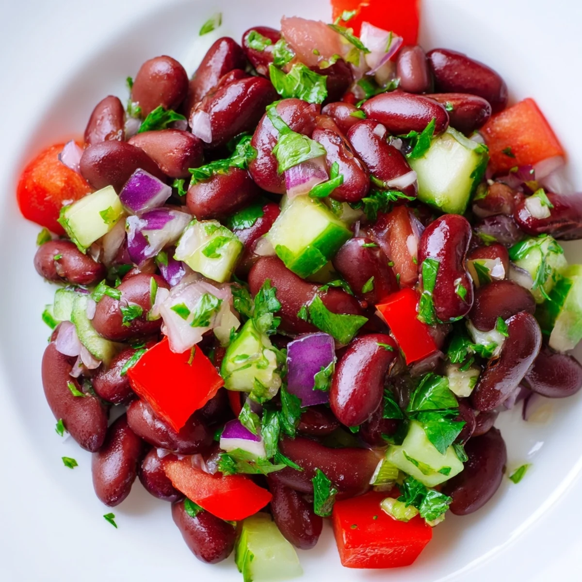 Colorful kidney bean salad in a white bowl with crisp bell peppers and tomatoes