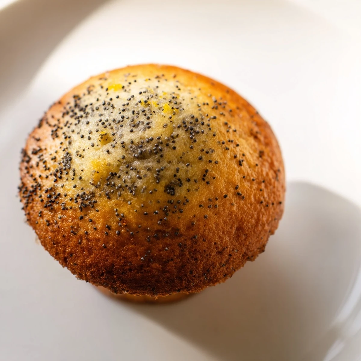 Golden lemon poppy seed muffins with domed tops fresh from the oven on a cooling rack