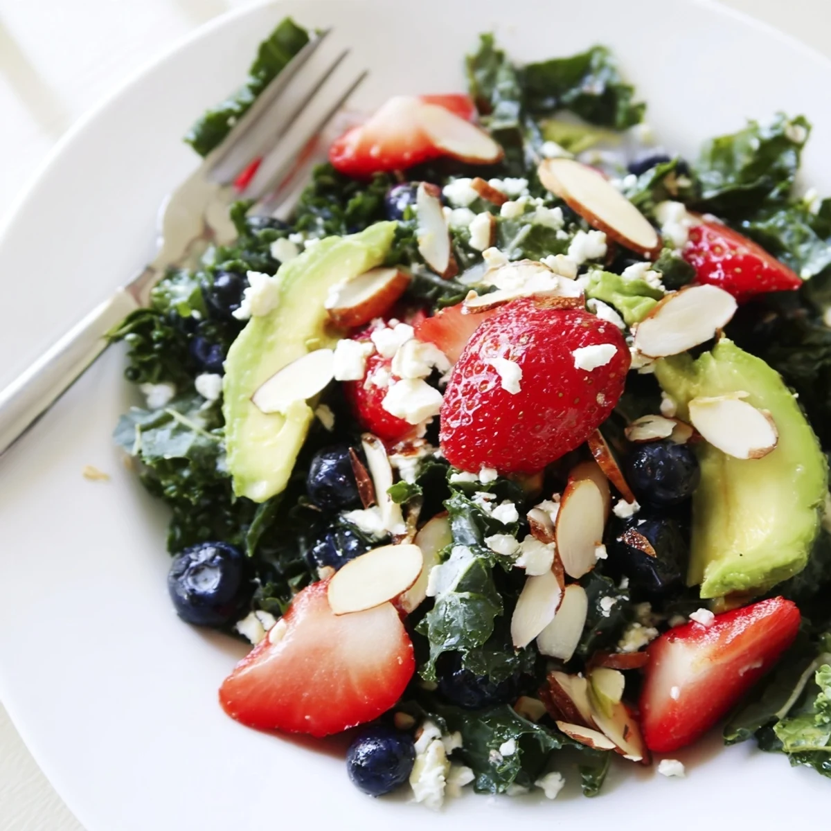 Summer kale salad topped with fresh berries, feta, and toasted almonds