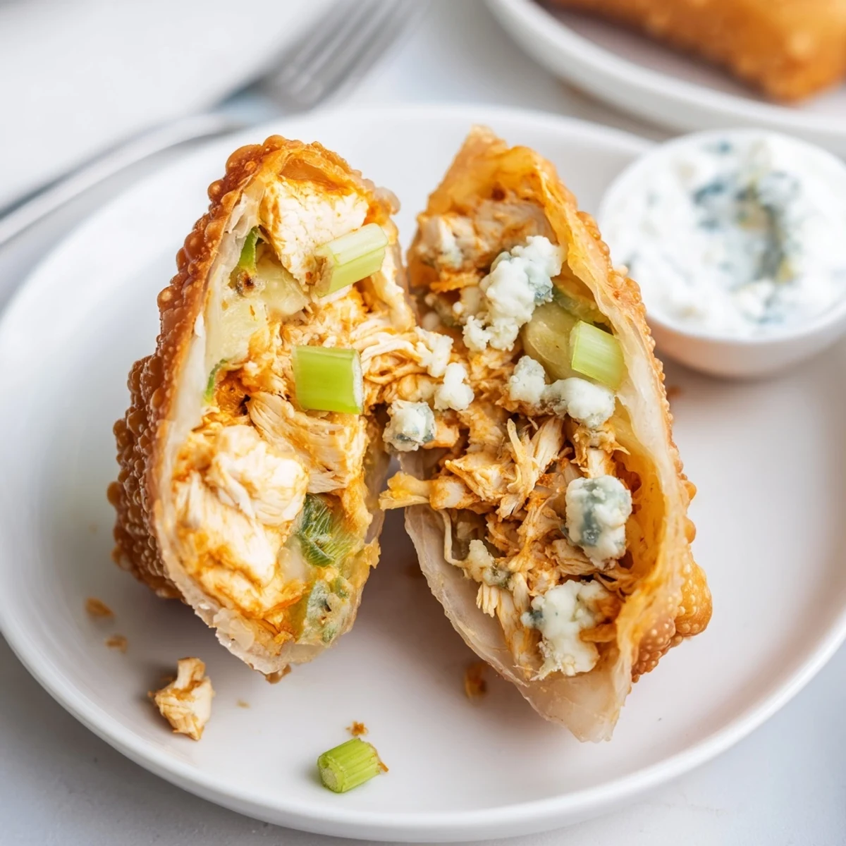 Plate of warm Buffalo Chicken Egg Rolls Recipe, crunchy fried shells, cooling on towels