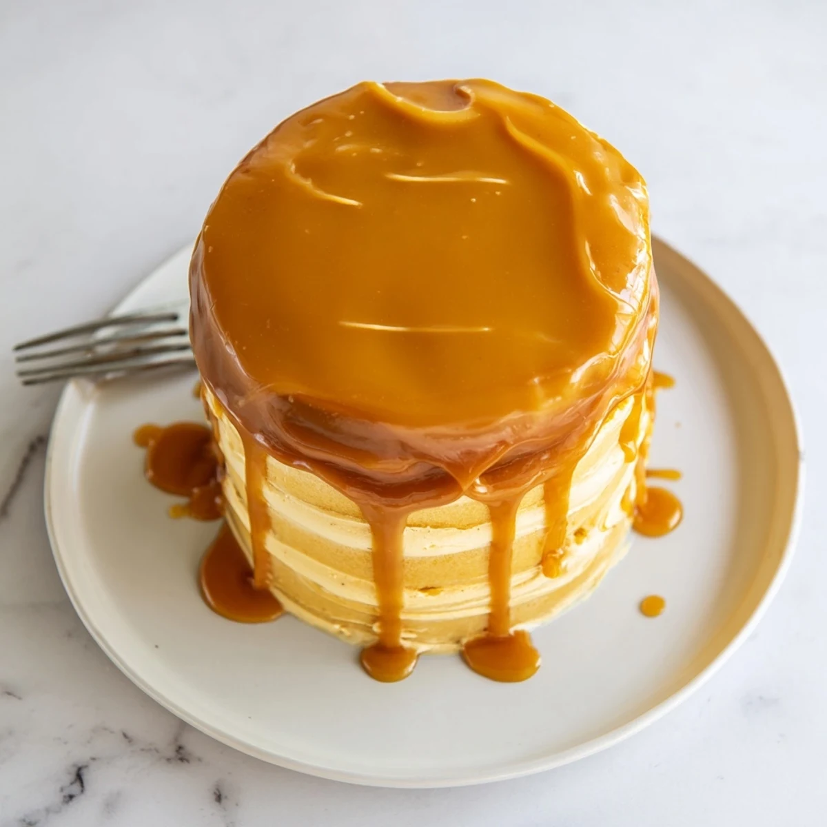 Golden caramel drizzle cascades down the sides of this decadent caramel cake with fluffy frosting