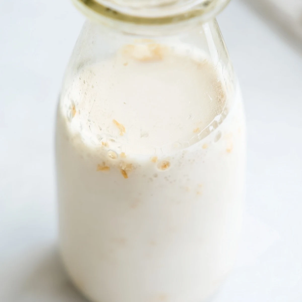 Fresh coconut milk being poured into a clear glass container
