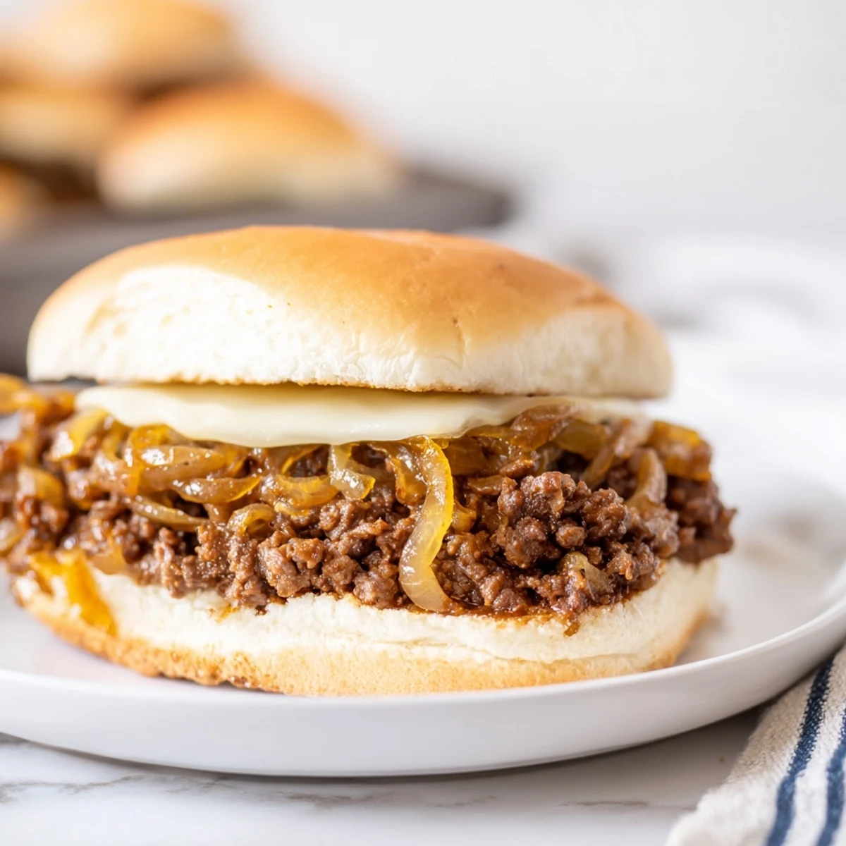 Open-faced sandwich featuring tender beef and sweet caramelized onions under bubbly Swiss cheese in this French Onion Beef Sloppy Joes recipe