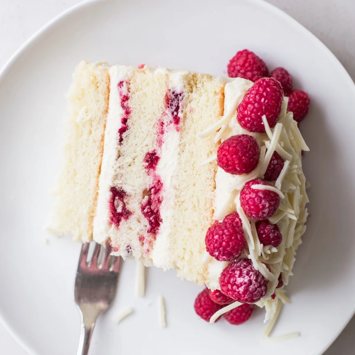 Elegant white chocolate raspberry dream cake layered with creamy frosting and fresh raspberries on a serving plate