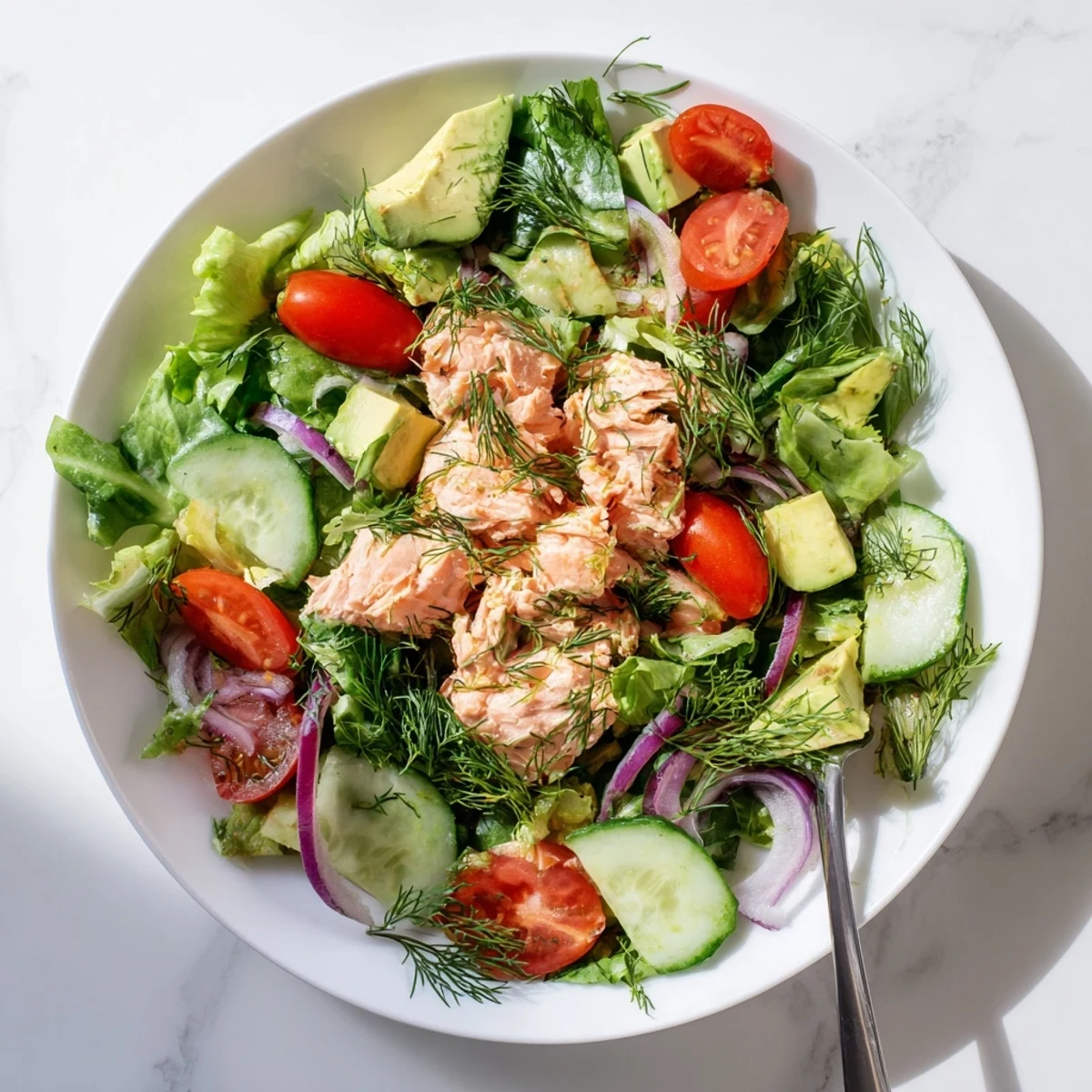 Flaky oven-roasted salmon served over vibrant salad bowl featuring ripe avocado juicy cherry tomatoes and tangy honey-lemon dressing