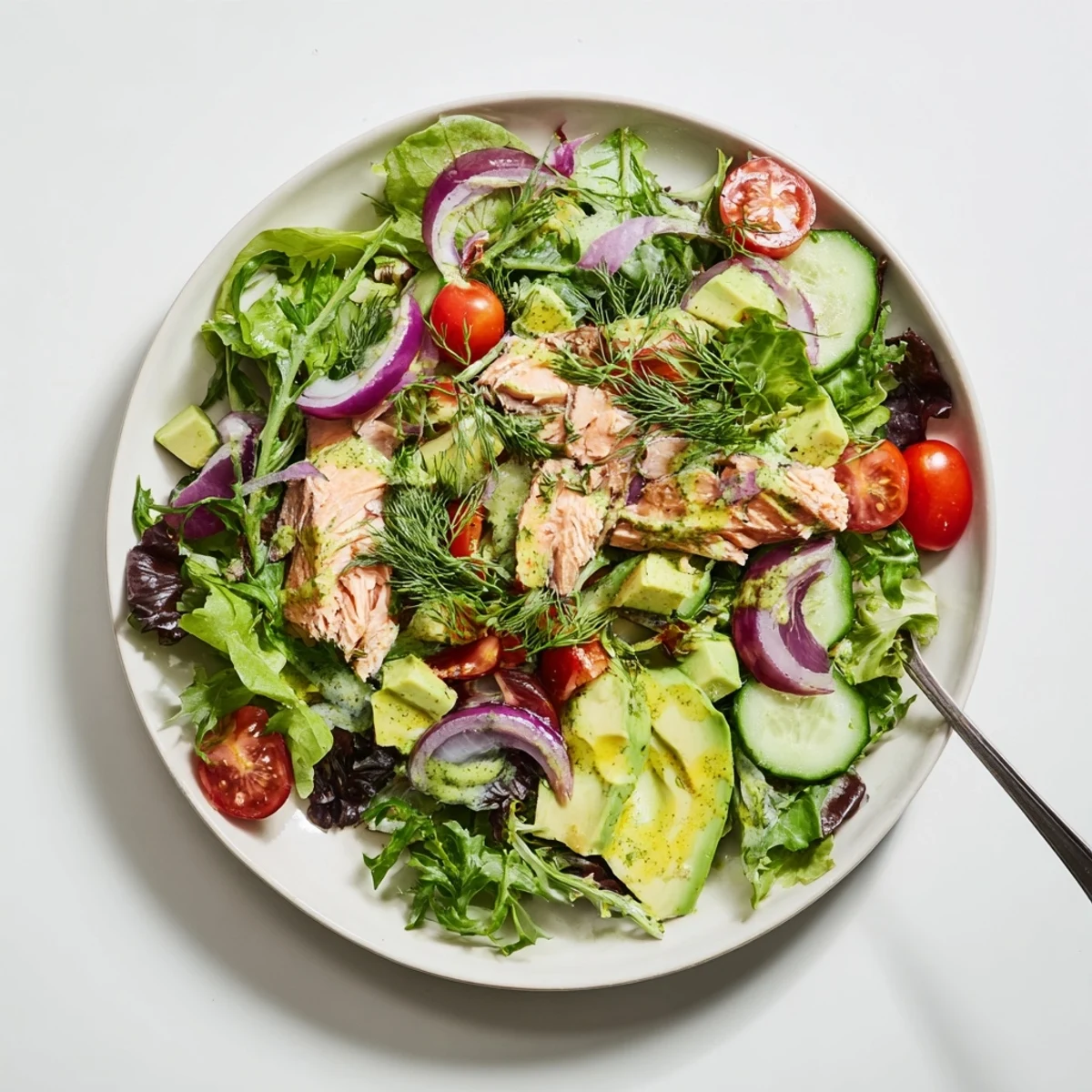 Protein-rich ultimate salmon salad with tender salmon pieces crisp vegetables creamy avocado and refreshing dill lemon vinaigrette on a white plate
