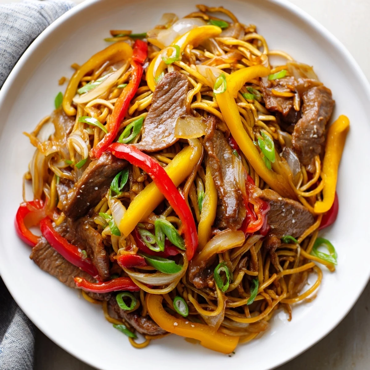 Savory beef chow mein stir-fry showcasing tender meat slices with crisp red and yellow peppers
