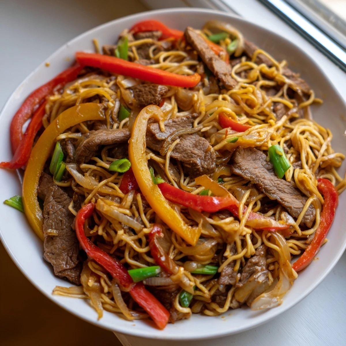 Golden beef chow mein noodles tossed with vibrant vegetables in a rich dark glossy sauce
