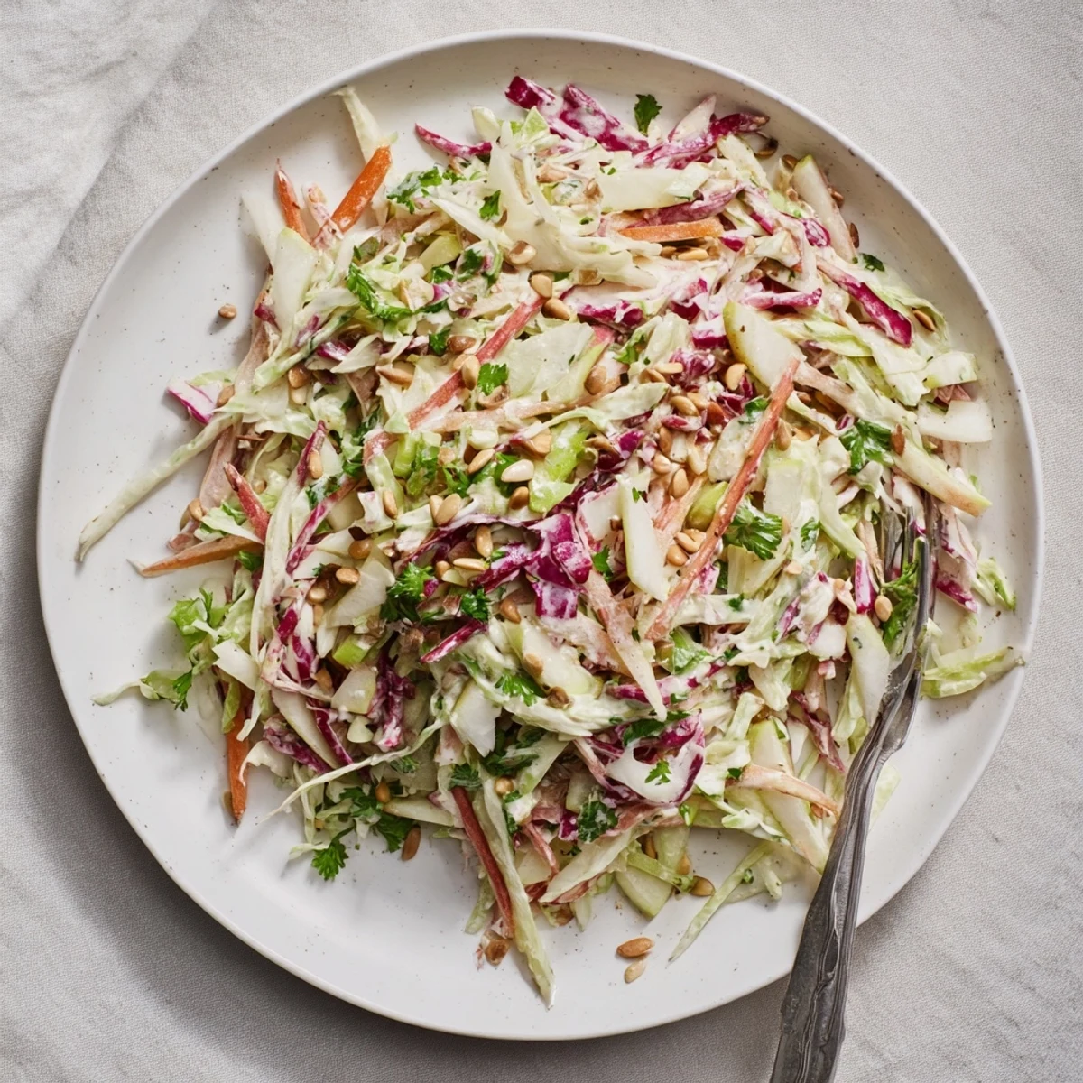 Colorful bowl of apple coleslaw topped with parsley and sunflower seeds for summer barbecues