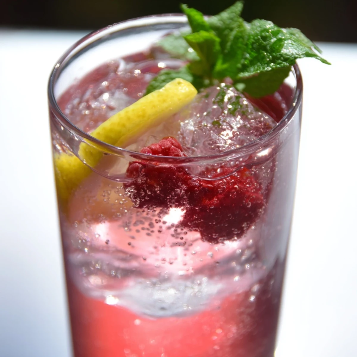 Sparkling honey lemon pink soda poured over ice with fresh mint and lemon slices