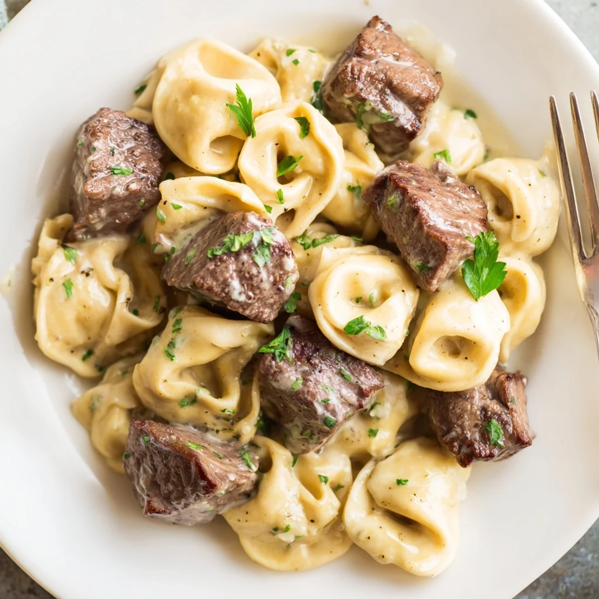 Golden garlic steak tortellini in a rich cream sauce garnished with parsley.