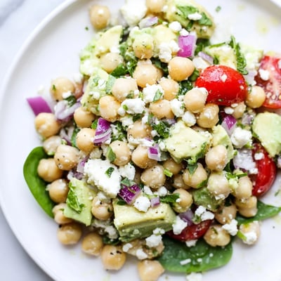 Crumbed feta and ripe avocado topping a colorful Mediterranean chickpea salad bowl