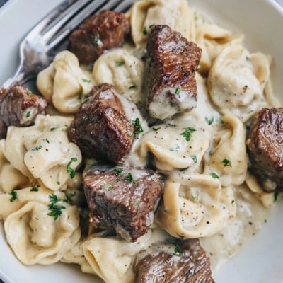 Savory steak and cheese tortellini coated in a creamy garlic parmesan sauce.
